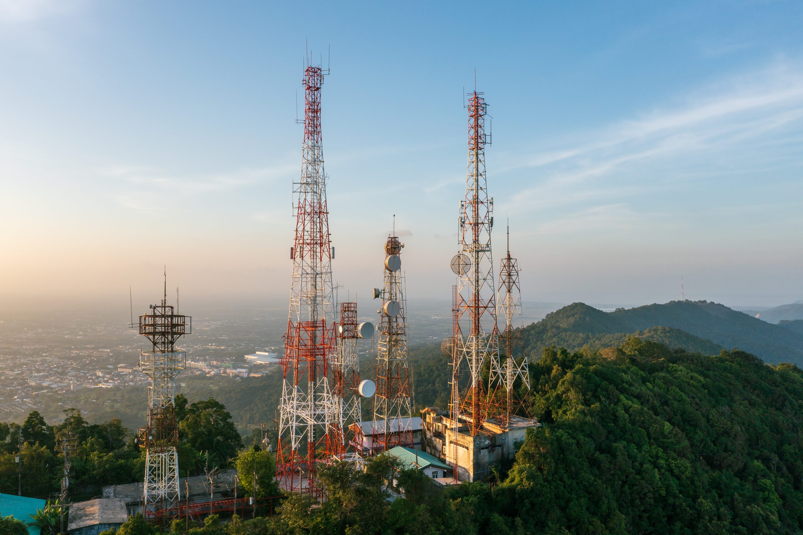 An aerial view of telecommunications towers located on a mountain during sunset.